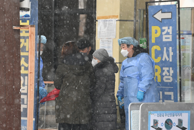 코로나19 신규 확진자가 98일 만에 최다인 8만8172명을 기록한 21일 오전 서울 송파구보건소 선별진료소에서 눈을 맞고 온 시민들이 유전자증폭(PCR) 검사장으로 들어서고 있다.  김호웅 기자