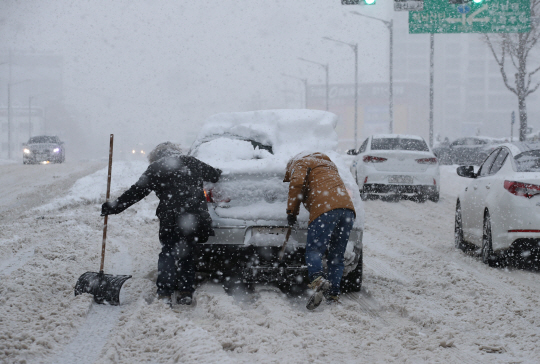 광주ㆍ전남 지역에 폭설경보가 발효된 23일 광주 서구 죽봉대로에서 시민들이 눈길을 빠져나가지 못하고 있는 차량을 밀고 있다. 연합뉴스
