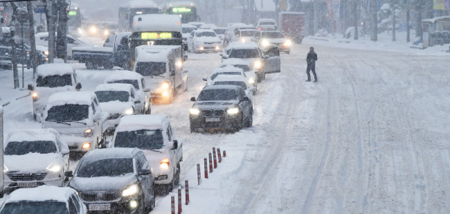 서울 등 중부지방 아침 기온이 영하 15도 내외로 떨어지는 등 올겨울 들어 가장 추웠던 23일 오전 대설경보가 내려진 광주 북구 문흥동 한 대로에서 운전자가 차에서 내려 쌓인 눈과 빙판길 탓에 움직이지 못하는 차량들을 바라보고 있다.   뉴시스