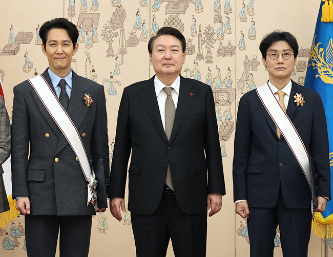 윤석열 대통령이 27일 서울 용산 대통령실 청사에서 ‘오징어게임’으로 미국 에미상 남우주연상을 받은 배우 이정재(왼쪽) 씨와 감독상을 받은 황동혁 감독에게 금관문화훈장을 수여한 뒤 기념촬영을 하고 있다. 연합뉴스