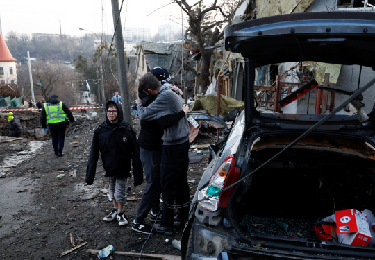 올해의 마지막 날인 31일(현지시간) 러시아의 공습을 받은 우크라이나 수도 키이우에서 주민들이 파괴된 건물과 자동차 사이에서 슬퍼하고 있다. 로이터·연합뉴스