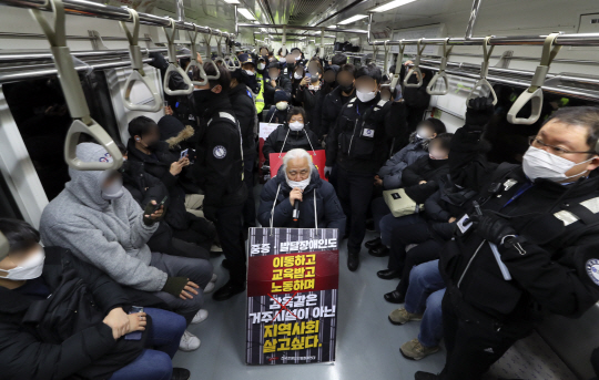 박경석(가운데 맨 앞) 전국장애인차별철폐연대(전장연) 대표가 지난해 12월 20일 오전 서울 광화문역에서 지하철에 탑승해 장애인 권리 예산 보장을 촉구하는 출근길 선전전을 하고 있다. 뉴시스
