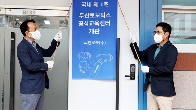 류정훈(오른쪽) 두산로보틱스 대표와 김익수 씨엔로봇 대표가 지난해 9월 대전에서 두산로보틱스 공식교육센터 개관 기념식을 하고 있다. 두산그룹 제공