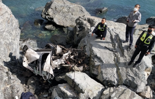 지난 12일 경남 거제시 남부면 해안도로 전망대를 뚫고 약 200ｍ 아래로 추락해 파손된 SUV 주변을 경찰이 살펴보고 있다. 연합뉴스·경남소방본부 제공