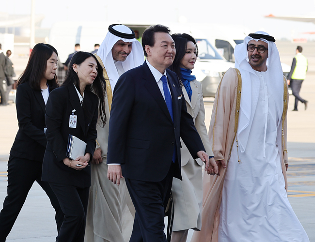윤석열 대통령과 김건희 여사가 14일(현지시간) 아랍에미리트(UAE) 아부다비 왕실공항에 도착, 공군 1호기에서 내려 영접나온 현지 관계자들과 함께 이동하고 있다. 연합뉴스