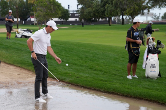 북아일랜드의 로리 매킬로이가 26일(한국시간) 아랍에미리트 두바이의 에미리트골프클럽에서 열린 DP월드투어 히어로두바이데저트클래식 1라운드 10번 홀에서 침수된 페어웨이 벙커에 빠진 공을 꺼내고 있다. AP뉴시스