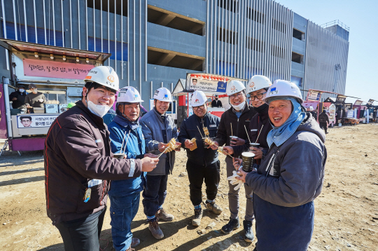 ㈜한화 건설부문 건설현장에서 근로자들이 ‘찾아가는 겨울간식차’에서 제공된 붕어빵과 어묵을 들고 환하게 웃고 있다. ㈜한화 건설부문 제공