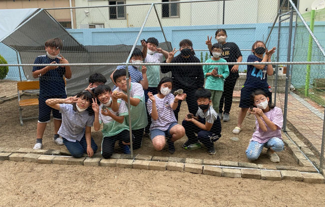 경북 청도군 중앙초 학생들이 지난해 5월 12일 손수 제작한 닭 사육장에서 환하게 웃고 있다.  초록우산어린이재단 제공