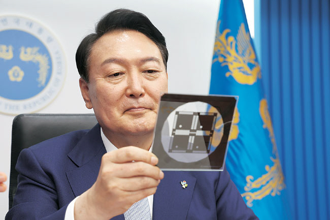 윤석열 대통령은 1일 경북 구미 금오공과대에서 과학기술 인력양성을 위한 제1차 인재양성전략회의를 개최했다. 사진은 윤 대통령이 지난해 6월 7일 용산 대통령실 국무회의에서 반도체 포토마스크를 살펴보는 모습.  뉴시스