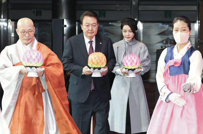 윤석열 대통령 부부와 진우 스님이 6일 코엑스에서 열린 불교계 신년대법회에서 헌등을 하기 위해 행사 도우미(오른쪽)의 안내를 받고 있다.   대통령실 제공