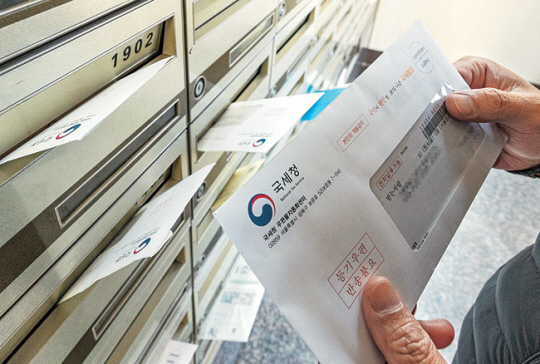 지난해 11월 23일 서울 송파구 한 아파트에서 주민이 우편함에 도착한 종합부동산세 고지서를 보고 있다. 연합뉴스