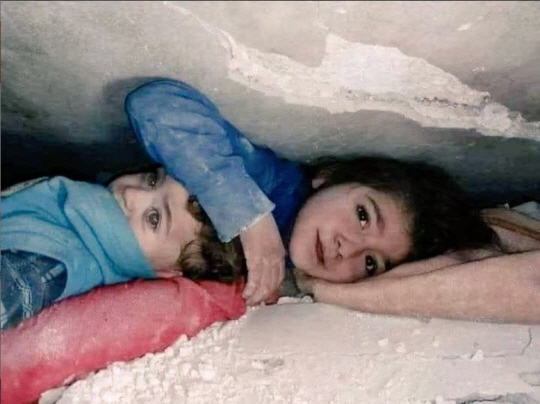 시리아의 지진 잔해 속에서 동생을 보호하고 있는 소녀의 모습. 트위터 캡처