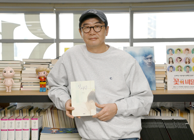 장진 감독이 지난달 20일 서울 중구 약수동 사무실에서 성석제의 단편집 ‘첫사랑’을 들고 포즈를 취하고 있다. ‘첫사랑’은 성향도, 체구도 다른 두 사춘기 소년의 사랑과 끌림을 묘사한다. 김호웅 기자