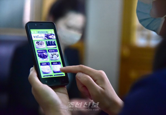 재일본조선인총연합회 기관지 조선신보는 7일 "조선에서 최근 손전화기용의 여러 자료열람프로그람들이 개발되어 사람들의 편의를 도모해주고 호평을 받고있다"고 보도했다. 사진은 요리 애플리케이션 화면 보고있는 북한 주민. 연합뉴스