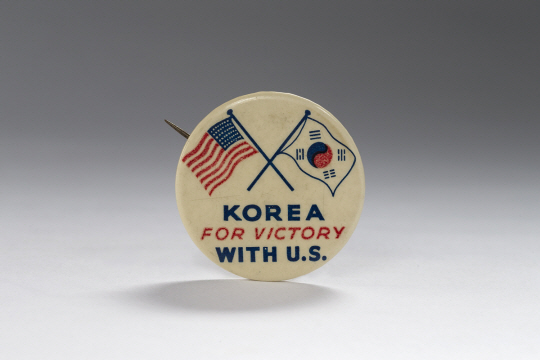 2차세계대전 당시 미국의 전쟁을 지원한 미주 한인들이 제작한 ‘승전기원 배지. 태극기와 성조기가 그려져 있고 &quot;승리를 위해 미국과 함께 싸우는 한국(Korea For Victory With U.S.)&quot;라는 문구가 적혀있다.  독립기념관 제공
