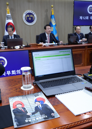 윤석열 대통령이 21일 서울 용산 대통령실 청사에서 한·일 정상회담 배경을 설명하는 가운데 맞은편의 한 국무위원 책상 위에 ‘한·일 새 출발하다’라는 제목으로 윤 대통령과 기시다 후미오 일본 총리가 악수하는 표지 사진이 실린 문화체육관광부 정책주간지 ‘K-공감’이 놓여 있다. 뉴시스