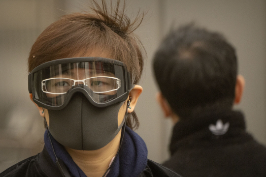 22일 중국 베이징의 중심가에서 한 시민이 마스크와 고글을 쓴 채 거리를 걷고 있다. 이날 아침 베이징은 황사와 모래폭풍으로 대기질 지수가 치솟았다. AP·뉴시스