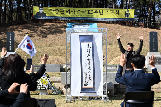26일 서울 용산구 효창공원 내 안중근 의사의 빈 무덤 앞에서 열린 ‘안중근 의사 순국 113주년 추모식’에서 안 의사의 동양평화 정신이 담긴 유묵이 첫 공개되자 참석자들이 대한독립 만세를 외치고 있다.   문호남 기자