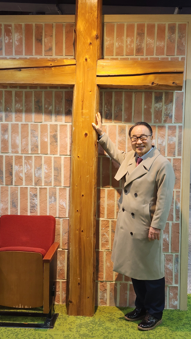 류영모 목사가 한소망교회 역사관에서 일산 마두동 시절(1997~2010)의 십자가와 함께 포즈를 취했다. 이 나무 십자가를 예배당 앞이 아닌 뒤쪽에 걸었는데, 신도들이 십자가를 통과해 나날이 새로워져야 한다는 상징이었다.