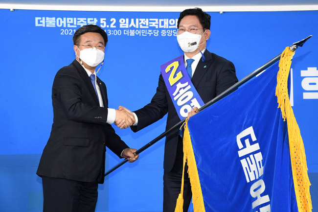2021년 5월 2일 서울 영등포구 여의동 더불어민주당사에서 열린 임시전국대의원대회에서 송영길 대표가 선출된 후 윤호중 원내대표에게 당기를 전달받고 있다. 뉴시스