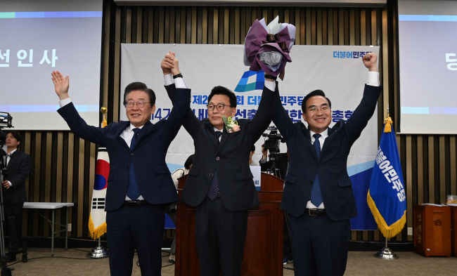 더불어민주당 신임 원내대표에 선출된 박광온(가운데) 의원이 28일 오전 서울 영등포구 여의동 국회에서 열린 민주당 의원총회에서 개표 후 이재명(왼쪽) 대표, 박홍근 전 원내대표와 함께 손을 잡고 기념촬영을 하고 있다. 박윤슬 기자