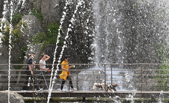 지난 2일 경기 안산시 노적봉 인공폭포를 찾은 시민들이 쏟아지는 폭포수를 바라보며 산책하고 있다. 뉴시스.
