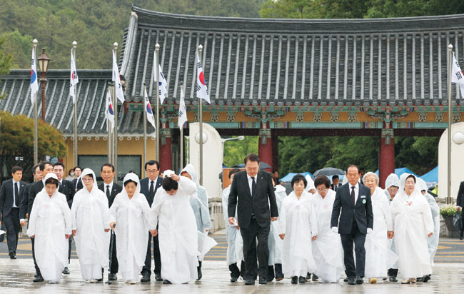 윤석열 대통령이 18일 오전 광주 북구 국립5·18민주묘지에서 열린 제43주년 5·18민주화운동 기념식에 참석하기 위해 오월어머니회 회원들과 함께 ‘민주의 문’을 지나 입장하고 있다. 연합뉴스