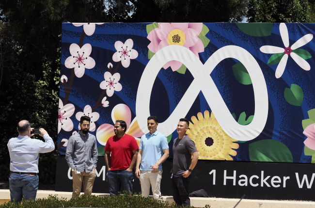 22일 미국 캘리포니아 멘로 파크에 위치한 메타의 본사 앞에 설치된 로고를 배경으로 방문객들이 기념사진을 찍고 있다. EPA 연합뉴스