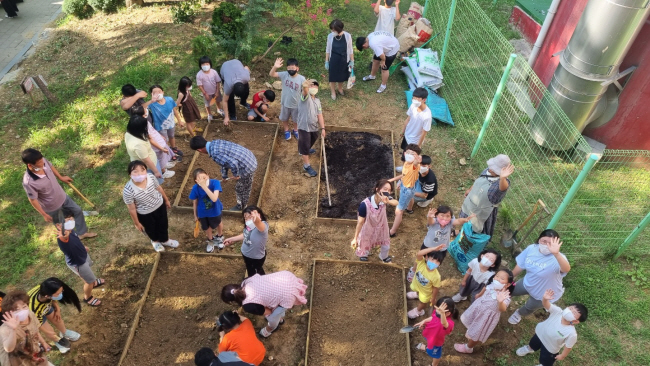 전주 완산구 평화종합사회복지관의 ‘다다익선’ 프로젝트에 참여한 아이들이 지난해 7월 27일 탄소 중립 식생활을 경험해보는 ‘지구의 식탁’ 프로그램의 일환으로 인근의 유휴지를 텃밭으로 일구는 활동을 해 보고 있다. 초록우산어린이재단 제공
