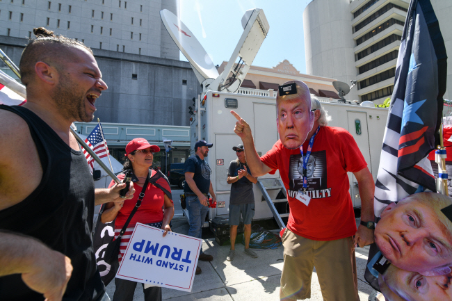 국가기밀 반출 혐의로 기소된 도널드 트럼프 전 미국 대통령의 13일 플로리다주 마이애미 연방법원 출석을 앞두고 트럼프 전 대통령 지지자들이 법원 앞에서 그의 얼굴 가면을 쓰고 ‘나는 트럼프를 지지한다’고 적힌 플래카드를 들고 출석을 기다리고 있다. EPA 연합뉴스