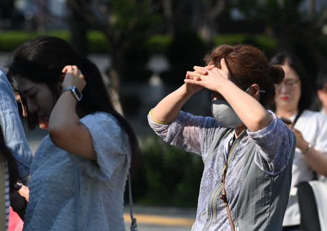 낮 최고 기온이 35도까지 오를 것으로 예보된 19일 오전 서울 광화문네거리에서 시민들이 햇볕을 손으로 가리면서 출근하고 있다.  윤성호 기자