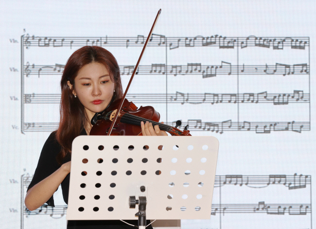 28일 열린 AI 편곡 서비스 ‘지니리라’ 발표회에서 연주자의 연주에 맞춰 AI가 음표를 그리고 있다. 연합뉴스