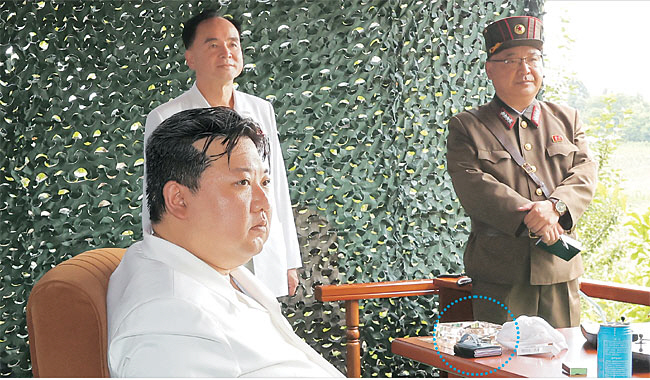 김정은 북한 국무위원장이 12일 대륙간탄도미사일(ICBM) 화성포-18형의 시험발사를 현지지도했다고 조선중앙통신이 13일 보도했다. 원 안은 김 위원장이 사용하는 것으로 보이는 ‘폴더블 스마트폰’. 외부에 케이스가 씌워진 상태에서 모양과 크기, 두께 등을 고려하면 삼성전자의 ‘갤럭시Z 플립’ 시리즈 제품일 가능성이 있다. 중국 화웨이 시리즈 제품일 수도 있다. 지난 3월 9일 김 위원장이 화성포병부대의 화력습격훈련을 현지지도할 당시 탁상에서 흰색 일체형 스마트폰이 포착된 것을 감안하면 최근 중국을 거쳐 제품이 은밀히 북한으로 들어갔을 것으로 보인다. 유엔 안전보장이사회는 전자기기 제품의 대북 수출입을 금지하고 있다.  연합뉴스