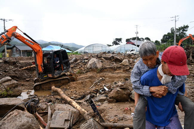 17일 오전 경북 예천군 감천면 진평리 산사태 사고 현장에서 한 마을주민이 반파된 이웃집에서 할머니를 업고 나오고 있다. 곽성호 기자