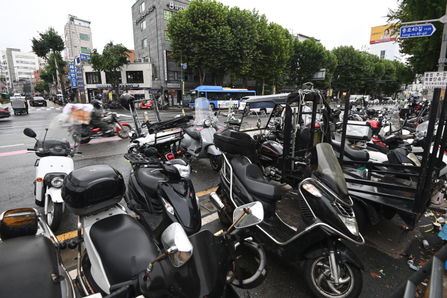 장마가 이어지는 가운데 18일 오전 서울 종로구 동대문상가 인근 길가에 배달용 오토바이들이 줄줄이 주차돼 있다.  문호남 기자