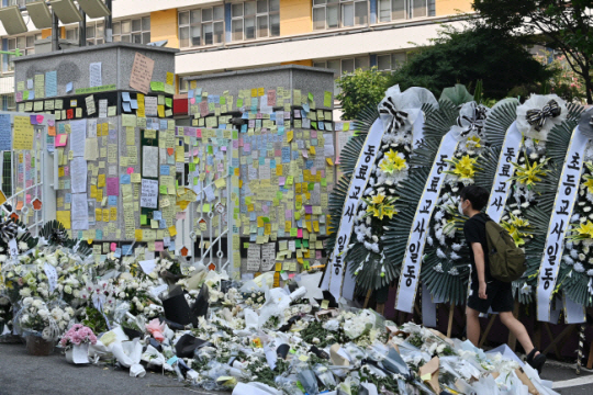 지난 21일 서울 서초구 서이초교 정문 앞에 극단적 선택을 한 교사를 추모하기 위한 근조 화환과 추모 메시지들이 가득 모여있는 가운데 한 학생이 등교하고 있다. 백동현 기자
