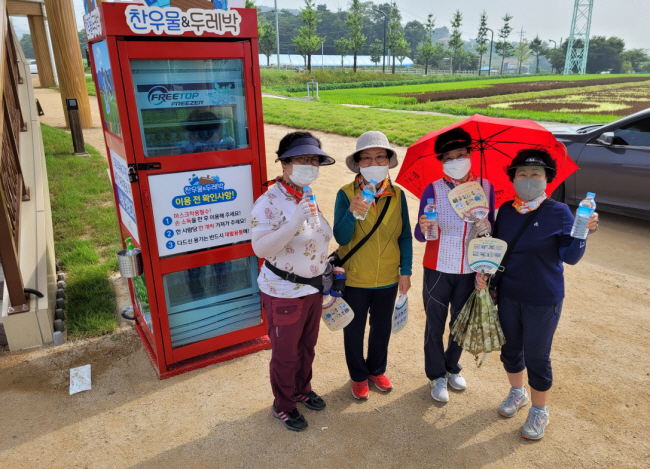 충북 제천시 주민들이 지방자치단체가 설치한 무인 냉장고 ‘찬우물&두레박’ 앞에서 더위를 식히고 있다.  제천시청 제공