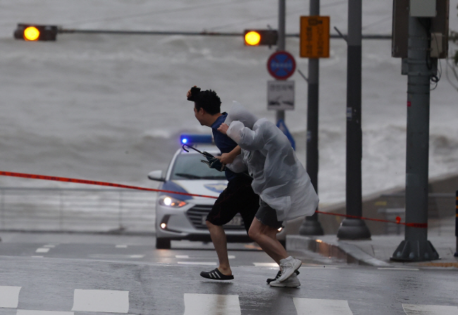 태풍 ‘카눈’이 남해안에 상륙한 10일 오전 부산 미포항 부근에서 주민들이 힘겹게 강풍을 뚫고 걸어가고 있다.    연합뉴스