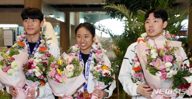 2023 세계배드민턴연맹(BWF) 세계개인선수권대회 여자 단식에서 우승한 안세영(가운데) 선수가 남자복식에서 우승한 강민혁(왼쪽), 서승재 선수와 함께 지난 29일 인천국제공항을 통해 귀국해 꽃다발을 받고 기념촬영을 하고 있다. 뉴시스