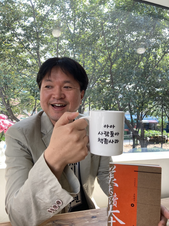 출판계 기획의 귀재로 손꼽히는 김홍민 북스피어 대표가 자신의 아이디어로 제작한 머그잔을 손에 들고 웃고 있다.