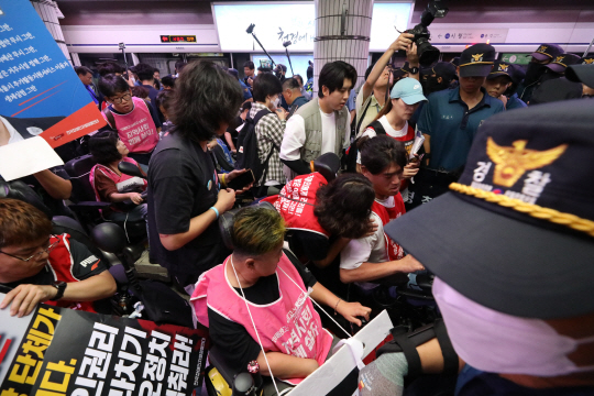 전국장애인차별철폐연대(전장연) 회원들이 5일 서울 지하철 1호선 서울시청역에서 열린 2024년 장애인권리예산 쟁취 및 오세훈 서울시장 혐오정치 고발 ‘출근길 지하철 탑니다’ 선포 기자회견에서 지하철 탑승을 위해 경찰과 대치하고 있다. 뉴시스