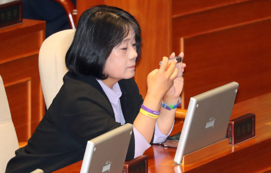 윤미향 무소속 의원이 8일 오후 서울 여의도 국회 본회의장에서 열린 제410회국회 본회의 교육·사회·문화 분야 대정부 질문에 참석해 휴대폰을 보고 있다. 뉴시스