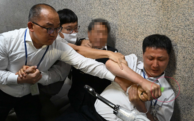 15일 이재명 더불어민주당 이재명 대표가 단식 중인 국회 당대표실 앞에서 혈서를 쓴다며 커터칼을 든 시민을 국회 직원들이 제지하고 있다. 연합뉴스