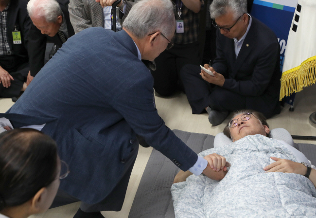 단식 16일 차를 맞은 이재명(오른쪽) 더불어민주당 대표가 15일 오전 서울 영등포구 국회 당 대표실을 찾아온 이부영(왼쪽) 자유언론실천재단 이사장 등 종교계 및 시민사회단체 원로들을 누운 채로 만나고 있다. 국회사진기자단