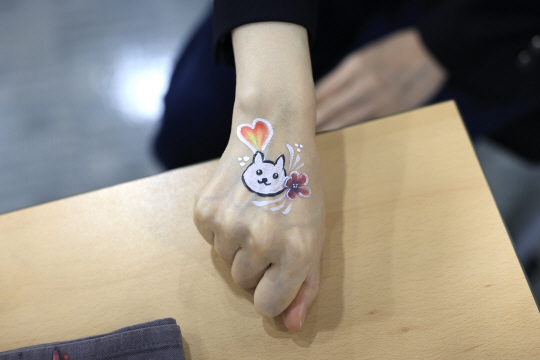 윤석열 대통령 부인 김건희 여사가 지난달 30일 서울 중구 프레스센터에서 열린 개식용 종식 촉구 기자회견에 참석해 한 참석자가 손등에 그려준 강아지 그림을 보이고 있다. 뉴시스