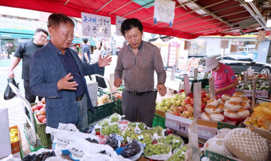 양충연 대한장애인체육회 사무총장(사진 왼쪽)이 25일 서울시 송파구 방이동 방이시장을 찾아 과일을 구매하며 소상공인과 이야기를 나누고 있다. 대한장애인체육회 제공