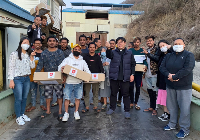 가톨릭근로자회관의 이관홍(오른쪽 다섯 번째) 신부 등 회관 봉사자들이 코로나19 유행 당시 이주노동자들에게 구호물품을 전달한 뒤 기념촬영에서 손가락 하트 포즈를 취하고 있다.   아산사회복지재단 제공