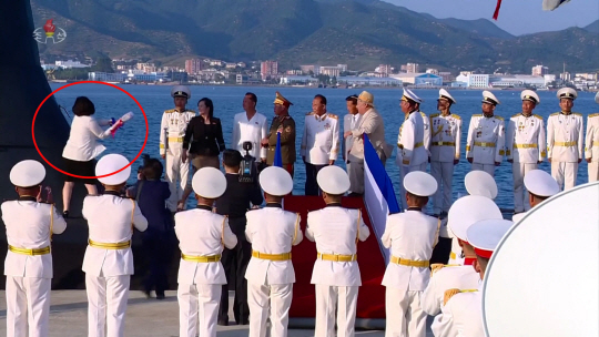 최선희(붉은색 동그라미) 북한 외무상이 김정은 북한 국무위원장이 참석한 가운데 지난달 6일 열린 전술핵공격잠수함 ‘김군옥영웅함’의 진수식에서 삼페인을 깨뜨리고 있다. 조선중앙TV 화면 캡처·연합뉴스