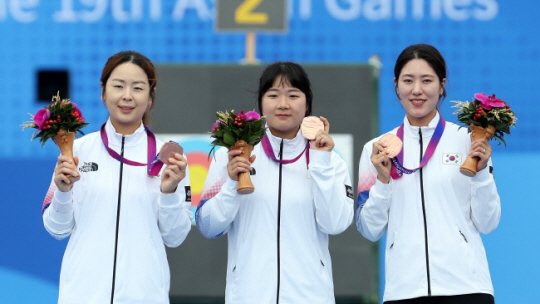 오유현(왼쪽부터), 조수아, 소채원이 5일 중국 저장성 항저우의 푸양 인후 스포츠센터에서 열린 2022 항저우아시안게임 양궁 여자 컴파운드 단체전에서 동메달을 획득한 뒤 환하게 웃고 있다. 뉴시스