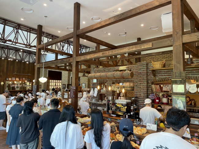 지난 2021년 9월 서울 안국동에서 문을 연 뒤 베이글 열풍을 일으킨 지역 베이커리 ‘런던 베이글 뮤지엄’은 조용히 입소문을 타며 유명 상권으로 연이어 진출하고 있다. 지난 8월 서울 송파구 잠실동 롯데월드몰에 입점한 런던 베이글 뮤지엄 매장 안에서 고객들이 긴 대기 줄을 만들고 있다.  롯데백화점 제공